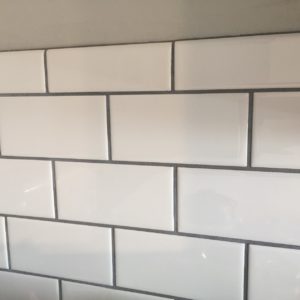 white subway tile backsplash with dark gray grout